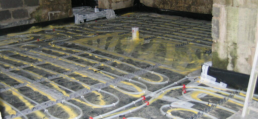 Underfloor heating pipes laying on the ground, with insulation underneath.  These are ready for concrete to be poured to create the floor