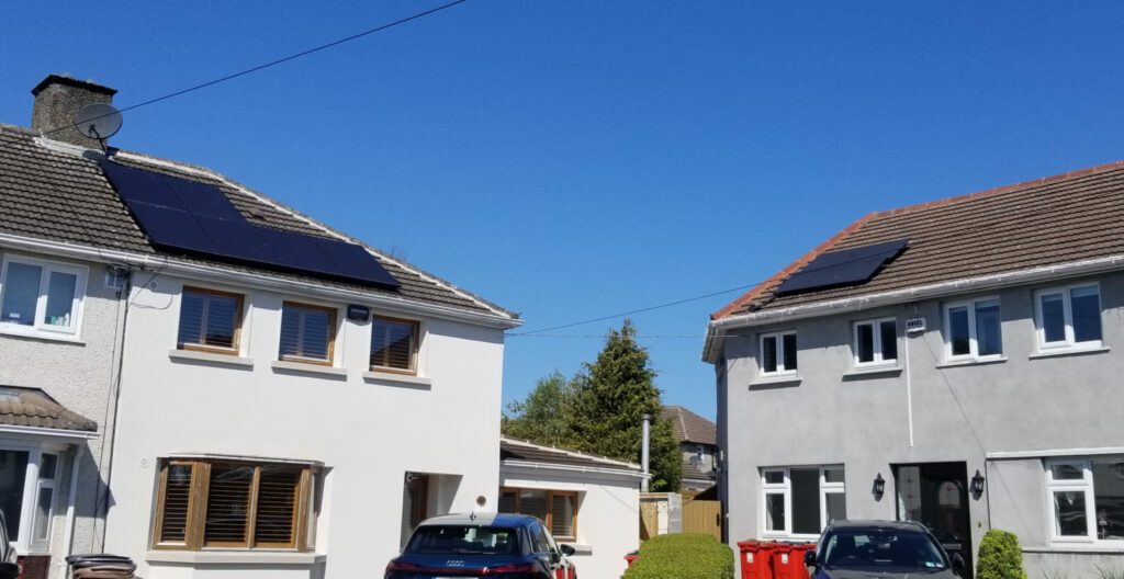 Image showing two neighbouring in Ireland.  The house on the left has solar PV panels, while the house on the right has solar thermal panels.  Notably, the PV solar panels occupy much more space than the solar thermal panels.